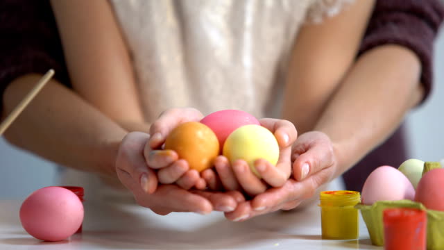 Daughter-and-mother-hands-holding-colorful-eggs-together,-Easter-holiday,-art