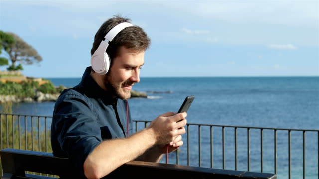 Glücklicher-Mann-anhören-von-Musik-auf-einer-Bank-sitzend