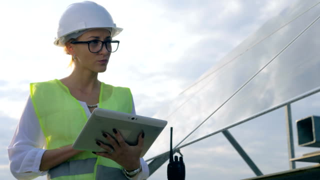 Female-engineer-works-with-a-tablet-near-solar-panels,-close-up.
