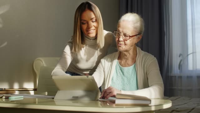 Großmutter-lernt-digitales-Tablet-mit-Hilfe-junger-Frauen