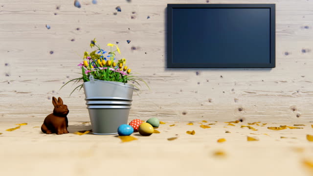 Huevos-de-Pascua-y-conejo-de-chocolate-cerca-de-un-cubo-de-flores-y-TV-de-pantalla-plana
