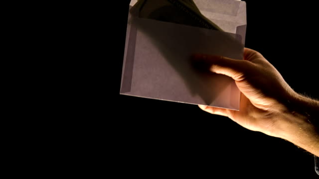 Hand-giving-envelope-with-money-isolated-on-black,-corruption-or-illegal-salary
