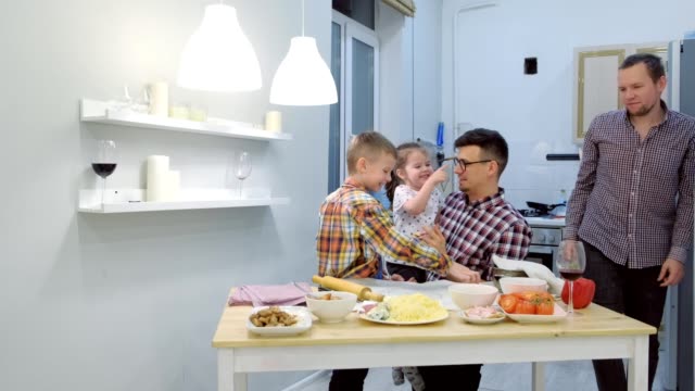 Gay-family-with-two-kids-cook-pizza-and-play-together-in-the-kitchen.