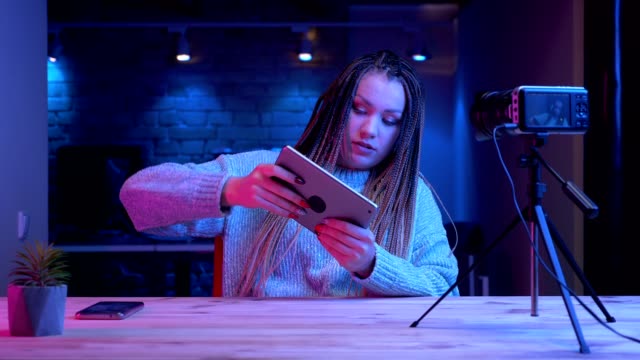 Closeup-Shooting-von-jungen-attraktiven-Bloggerinnen-mit-Dreadlocks-spielen-Videospiele-auf-dem-Tablet-scheitern-und-frustriertes-Streaming-live-mit-dem-neon-Hintergrund-drinnen