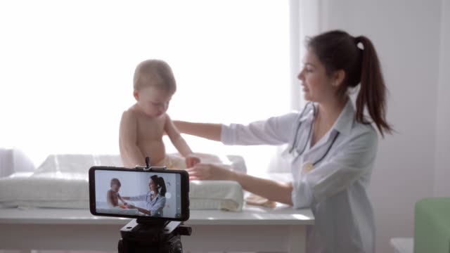 formación-en-línea,-famoso-Vlogger-Girl-doctor-grabación-de-vídeo-en-las-redes-sociales-en-el-teléfono-celular-durante-el-examen-médico-de-niño-en-streaming-en-vivo