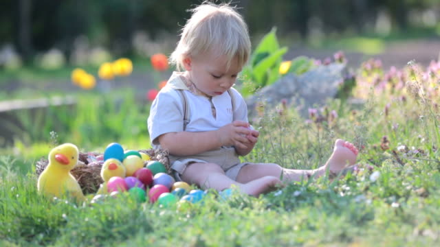 Sweet-toddler-boy-with-bunny-ears,-egg-hunting-for-Easter,-child-and-Easter-day-traditions.-Kids-and-holidays