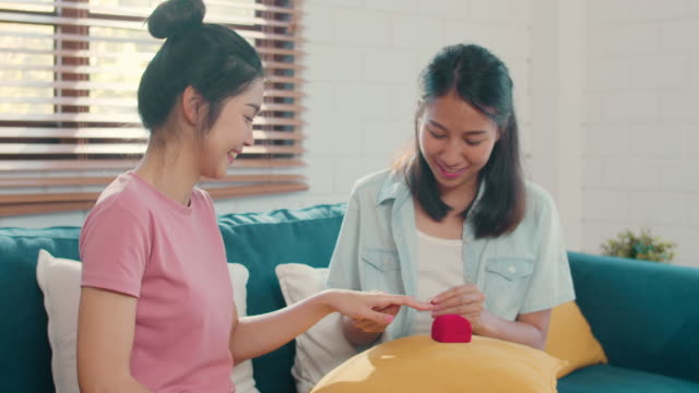 Asiatische-Lesben-lgbtq-Frauen-Paar-vorschlagen-und-Ehe-Überraschung-tragen-Ehering-zu-Hause.
