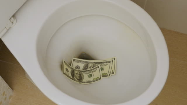 Geldverschwendung.-Hand-wirft-Dollar-Scheine-in-die-Toilette.-Closeup
