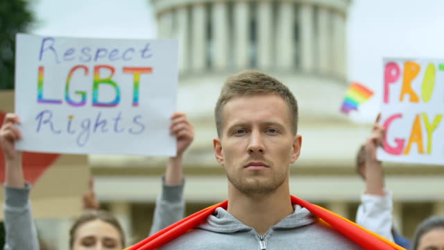 Junger-Mann-hisst-Regenbogenfahne,-LGBT-Rechte-Rallye-Teilnehmer,-Stolz-Marsch