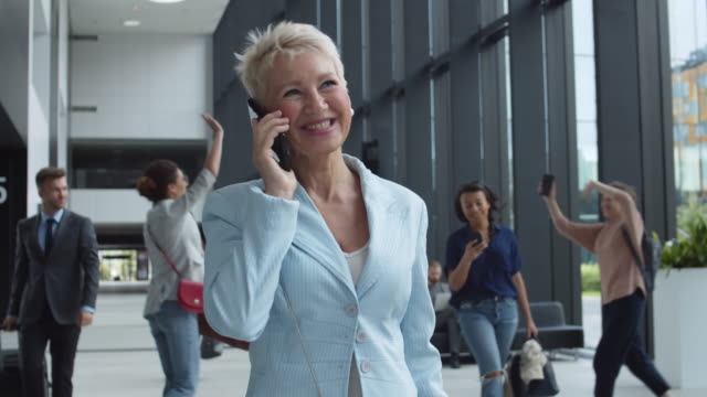 Frau-mittleren-Alters-plaudert-am-Telefon-am-Flughafen