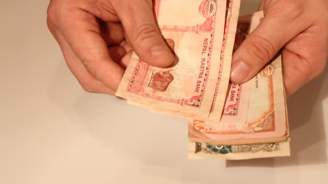 Die-Hände-des-Mannes-zählen-nepalesische-Rupee-Banknoten.-Nationale-Währung-Nepals-(NPR)