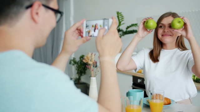 Slow-motion-of-lady-posing-with-apples-when-guy-taking-photo-with-smartphone