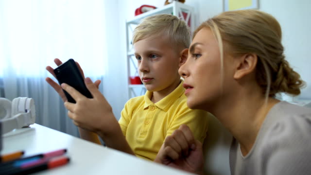 Lindo-niño-que-muestra-madre-nueva-aplicación-de-teléfono-inteligente,-tecnologías-modernas,-gadgets