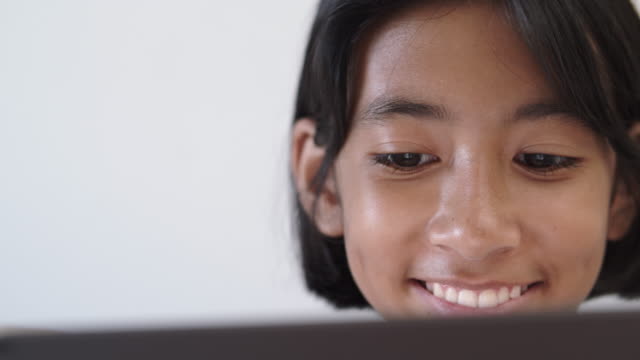 Close-up-of-Asian-girl-watching-video-via-online-media-On-tablet-for-entertainment-And-smiling-happily-while-sitting-on-the-sofa