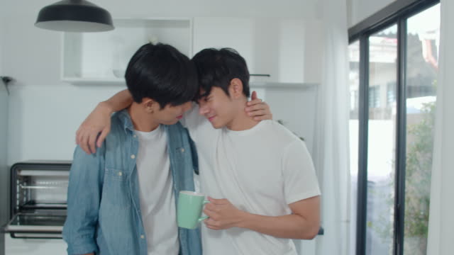 Asian-gay-couple-drinking-coffee,-having-a-great-time-at-home.-Young-handsome-LGBTQ+-men-talking-happy-relax-rest-together-spend-romantic-time-in-modern-kitchen-at-house-in-the-morning-concept.