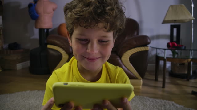 Absorbed-Caucasian-boy-watching-something-funny-at-smartphone-screen.-Cheerful-kid-looking-at-the-screen-and-laughing.-Generation-Z,-internet,-modern-technologies.-Cinema-4k-ProRes-HQ.