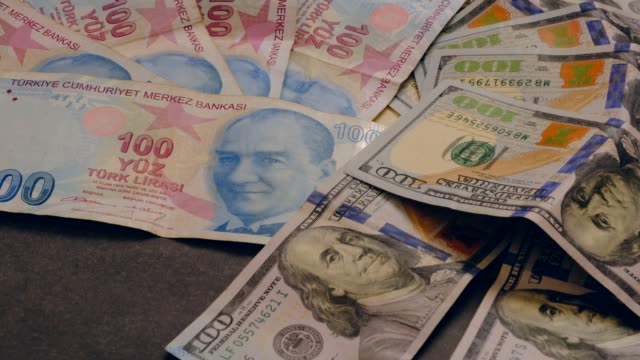 viele-usd-100-Dollar-und-100-türkische-Lira,-stehend-auf-dem-schwarzen-Boden