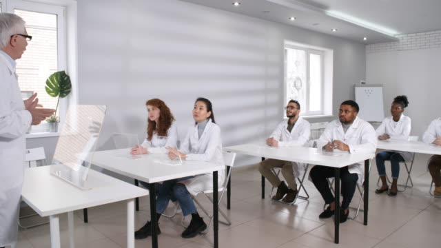Elderly-Teacher-in-Lab-Coat-Lecturing-in-Class-with-Futuristic-AR-Devices