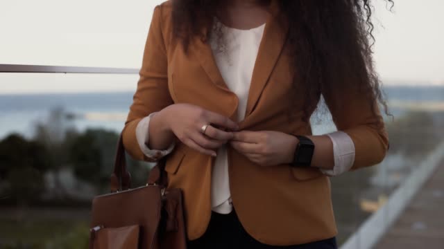 Businesswoman-with-smartwatch-buttoning-blazer-and-getting-ready-for-work