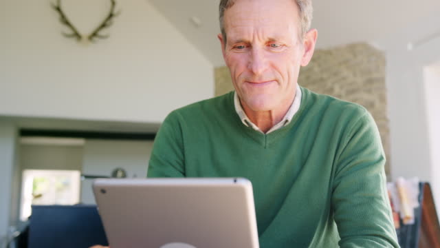 Hombre-senior-en-casa-comprando-bienes-o-servicios-en-línea-con-tableta-digital-y-tarjeta-de-crédito
