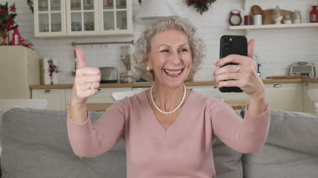 Pensioner-holds-telephone-in-hand-smiles-and-shows-cool-sign