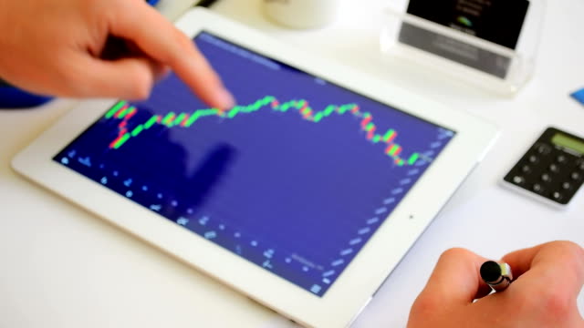 Hombre-de-negocios-trabajando-con-tableta-en-el-mercado-de-valores-en-línea-trading-floor