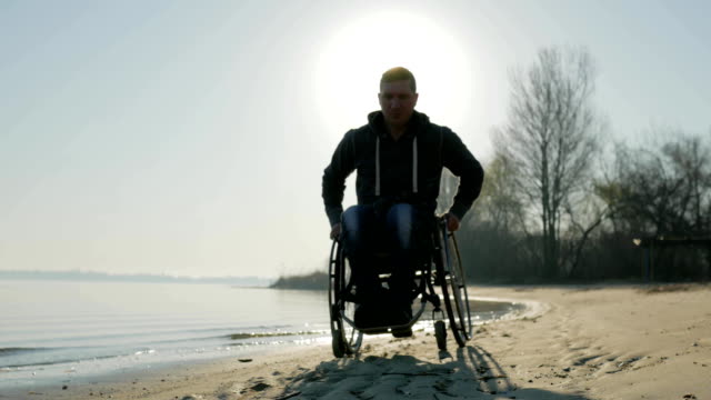 Man-with-disabilities-rides-along-beach-in-wheelchair
