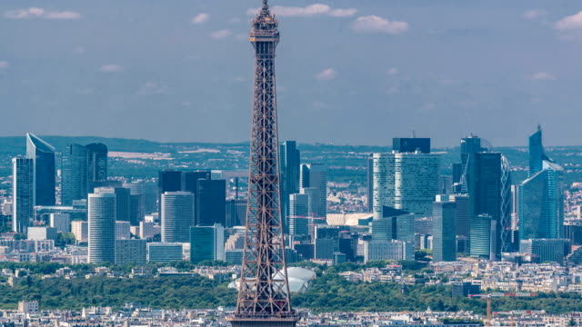 Vista-aérea-de-la-torre-de-Montparnasse-con-la-Torre-Eiffel-y-el-barrio-de-La-Defense-en-timelapse-de-fondo-en-París,-Francia