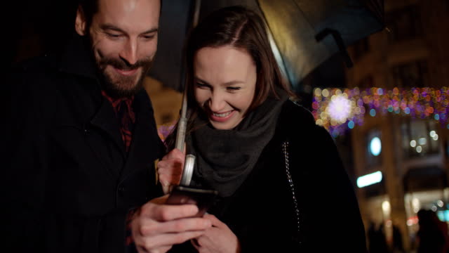 Young-happy-couple-using-smartphone-at-night.