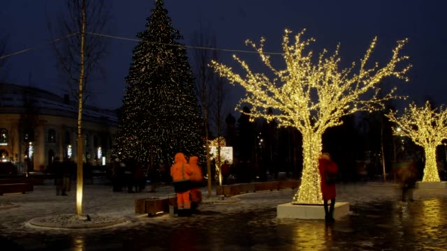People-walking-and-passing-by-Christmas-Tree-lights-and-mood-on-the-main-street-in-the-town-center.-Time-lapse