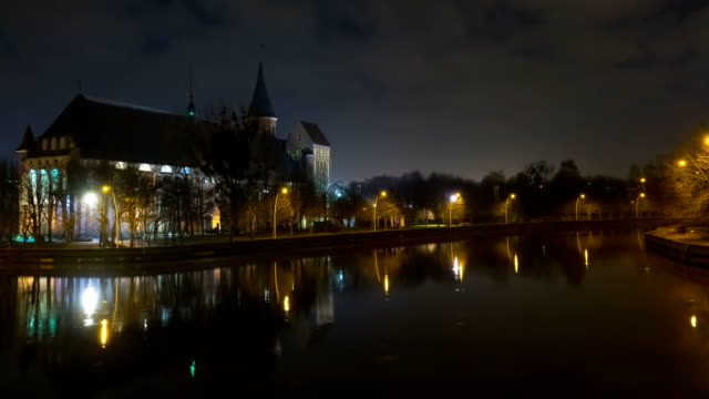 Illumination-on-a-historic-building.-Historic-Landmark.-Time-lapse.-Cathedral-of-Kant-in-Kaliningrad.-Old-medieval-castle-at-night-against-the-sky.-Timelapse.-City-park-with-a-river,-a-pond.