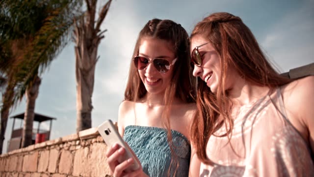 Las-mujeres-de-joven-inconformista-que-se-divierten-leyendo-el-mensaje-de-texto-en-la-playa