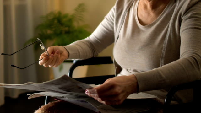 Mujer-con-discapacidad-tratando-de-leer-el-periódico-a-través-de-las-lentes,-mala-vista