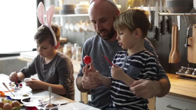 Father-helping-sons-to-color-Easter-eggs