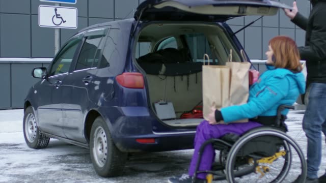 Hombre-cargando-bolsas-en-el-coche-con-mujer-parapléjico