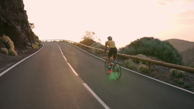 Radfahrer-sitzen-auf-einem-Fahrrad-auf-einem-Smartphone-für-social-Networking-Berglandschaft-bei-Sonnenuntergang-fotografieren.-Slow-motion