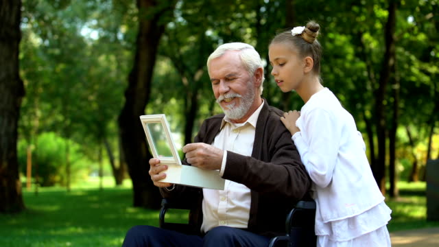 Großvater-im-Rollstuhl-mit-Enkelin-militärische-Token,-Geschichten-zu-erzählen