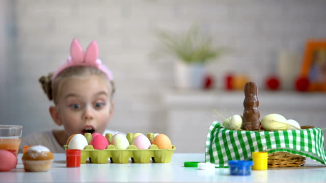 Muchacha-divertida-que-aparecen-por-debajo-de-la-mesa-y-mirar-con-entusiasmo-los-huevos-de-Pascua-teñidos