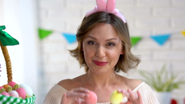 Cheerful-woman-having-fun-holding-brightly-colored-Easter-eggs-near-eyes,-mood