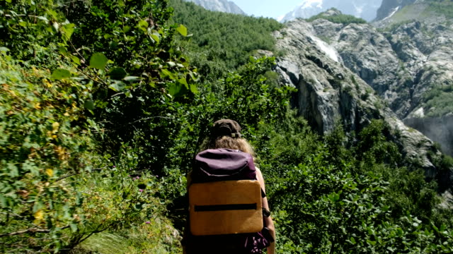 Woman-climber-hiker-tourist-with-a-backpack-in-the-trek-goes-along-the-route-against-the-backdrop-of-beautiful-scenery