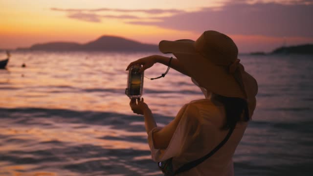 Beautiful-woman-taking-photos-with-smart-phone-technology-on-paradise-beach