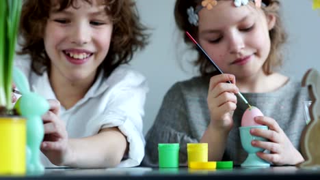 Close-portrait-of-a-boy-and-girl-with-paints-and-brushes.-Children's-Easter-creativity.-Brother-and-sister-decorate-Easter-eggs-and-laugh-merrily