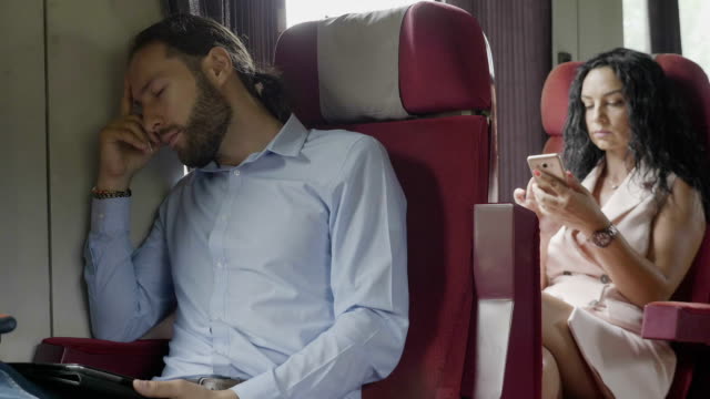 Durmiendo-joven-corporativo-hombre-viajero-y-mujer-usando-smartphone-navegando-en-Internet-mientras-viaja-en-tren-va-a-trabajar