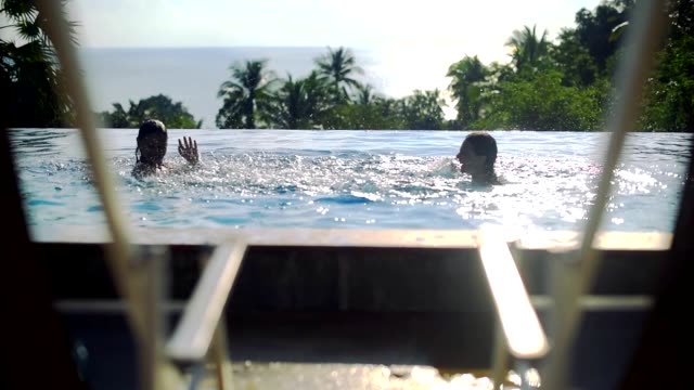 Two-girls-playing-in-the-outdoor-pool-on-a-sunny-day-on-a-tropical-island
