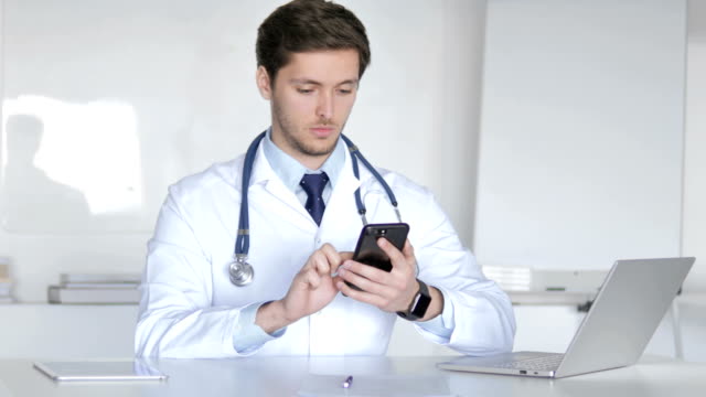 Joven-doctor-navegando-smartphone-en-clínica