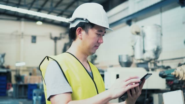 Junge-asiatische-männliche-Fabrikarbeiterin-mit-einem-digitalen-Tablet