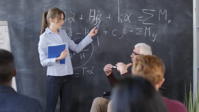 Student-Standing-at-Blackboard-and-Talking-to-Teacher