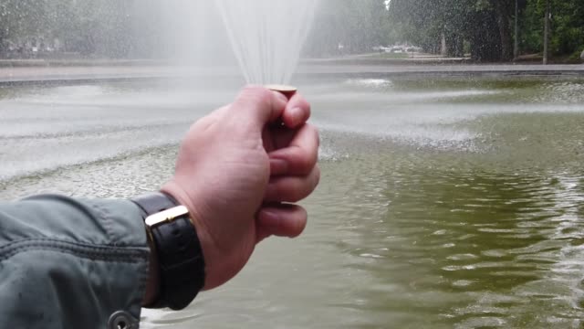 Male-and-female-hand-throws-a-coin-into-the-fountain-for-good-luck.