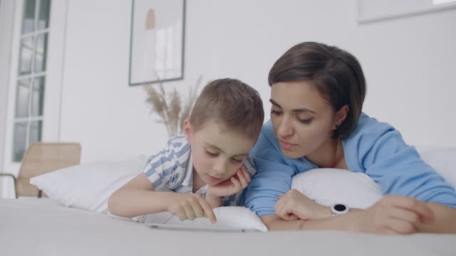 Happy-family-mother-and-child-son-with-tablet-in-evening.-Happy-family-mother-and-child-son-with-tablet-in-evening-before-bed.