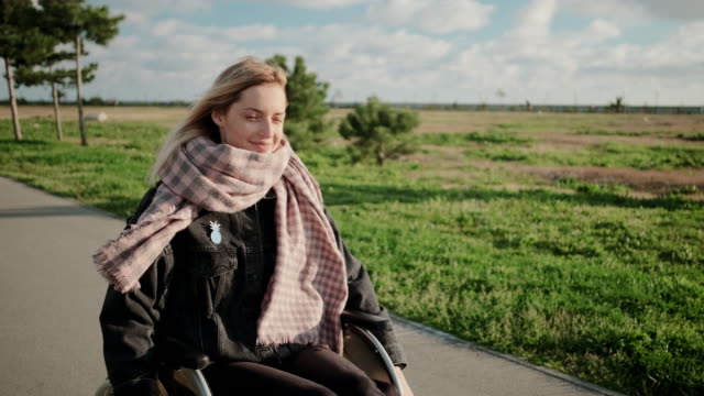 Lächelnde-behinderte-Frau-im-Rollstuhl-auf-angenehmem-Outdoor-Spaziergang